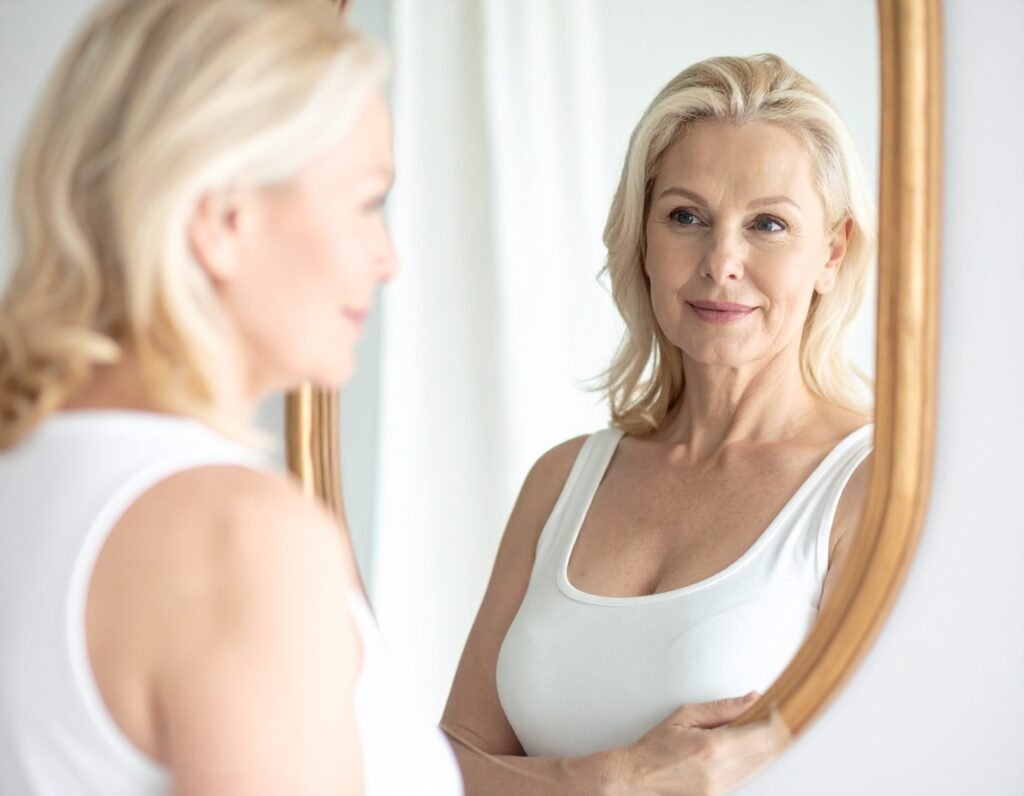 Woman standing confidently in front of mirror about to do a breast self exam